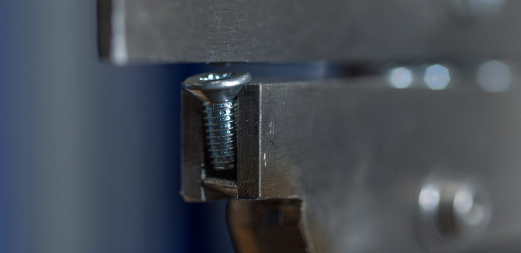A very close up view of a screw in a linear conveyor system being fed into a vibratory bowl sorter.